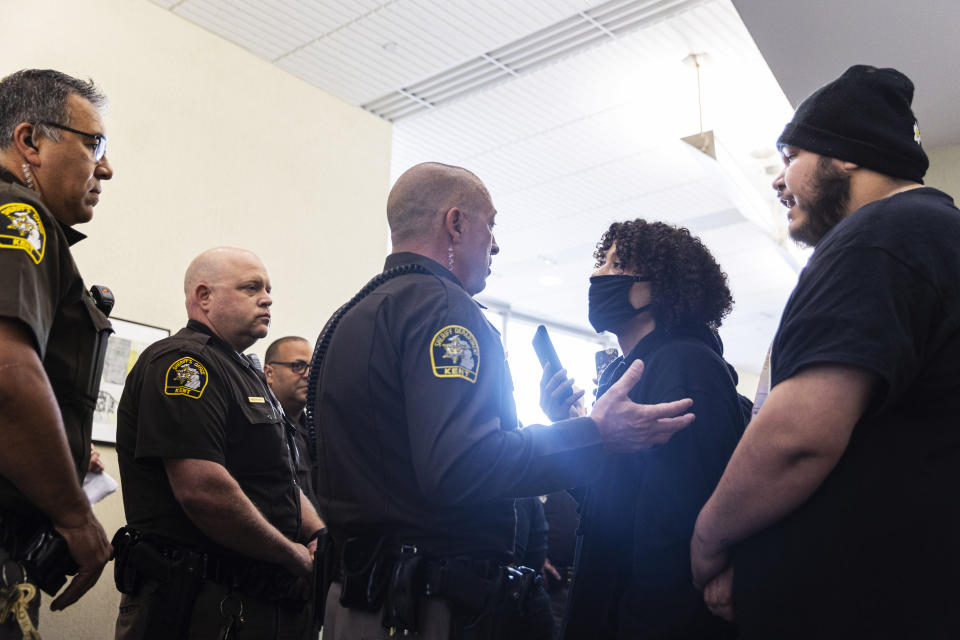 A Patrick Lyoya supporter talks with a Kent County Sheriff Deputy as supporters of Christopher Schurr also gather in the hallway outside of Kent County District Court as Grand Rapids Police officer Schurr appeared on video from jail, Friday, June 10, 2022 in Grand Rapids, Mich. A judge facing a packed courtroom set bond Friday at $100,000 for Schurr, a Michigan police officer charged with second-degree murder in the death of Patrick Lyoya, a Black man who was shot in the back of the head in April. (Joel Bissell/The Grand Rapids Press via AP)