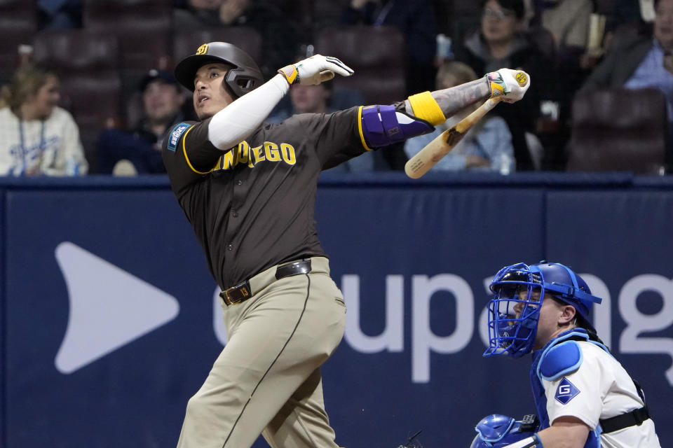 San Diego Padres' Manny Machado, left, hits a three-run home run as Los Angeles Dodgers catcher Will Smith watches during the ninth inning of a baseball game at the Gocheok Sky Dome Thursday, March 21, 2024, in Seoul, South Korea. (AP Photo/Ahn Young-joon)