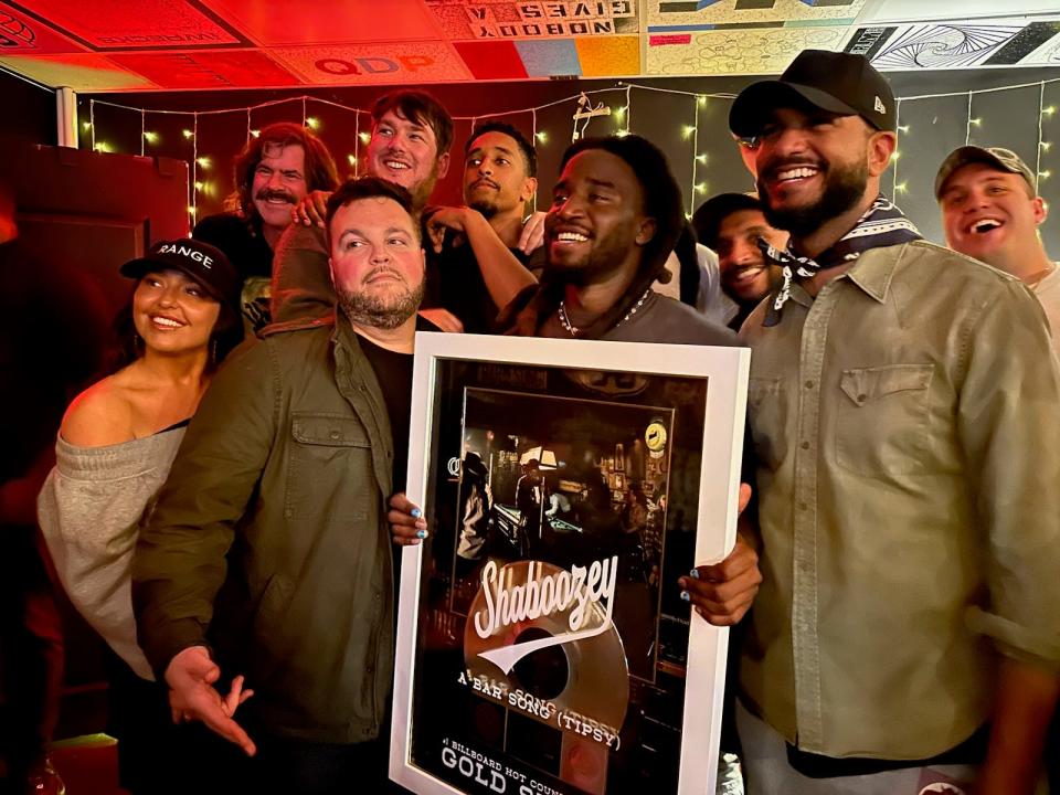 Shaboozey, with his management team and EMPIRE staffers, is presented with a gold record for ""A Bar Song (Tipsy)"'s success.