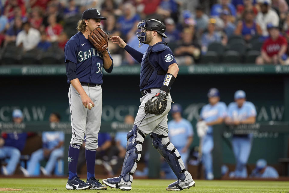 Seattle Mariners catcher Curt Casali, right, heads to the mound to settle starting pitcher Logan Gilbert (36) after they gave up two runs to the Texas Rangers during the fourth inning of a baseball game in Arlington, Texas, Sunday, Aug. 14, 2022. (AP Photo/LM Otero)