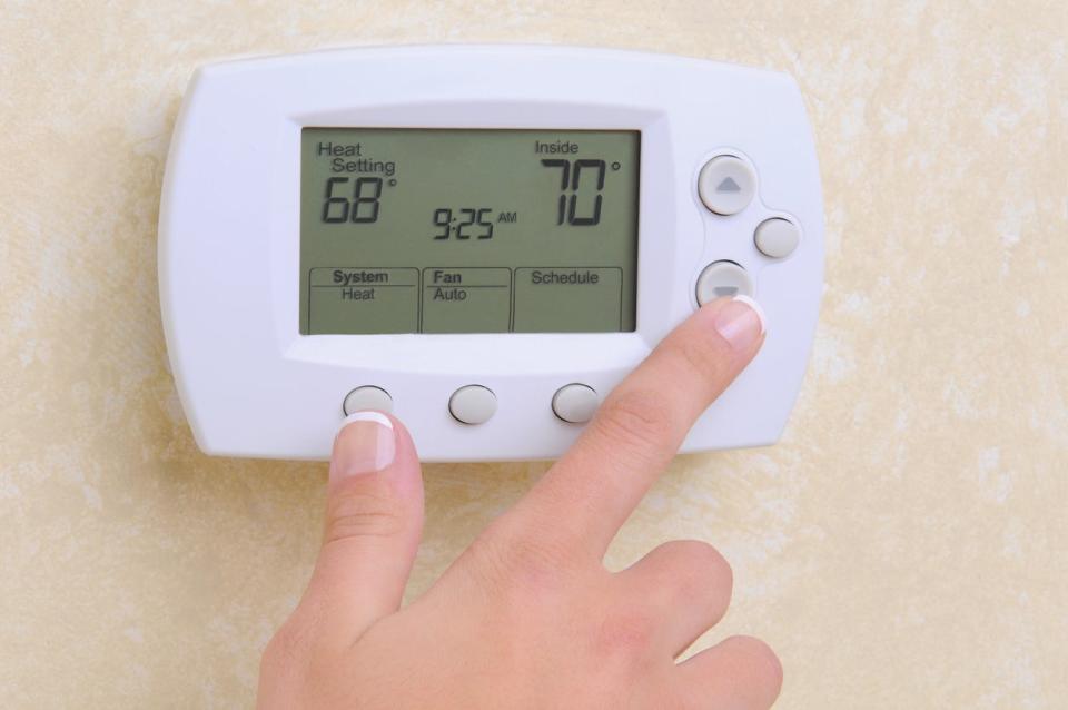 close up of hand adjusting thermostat on wall