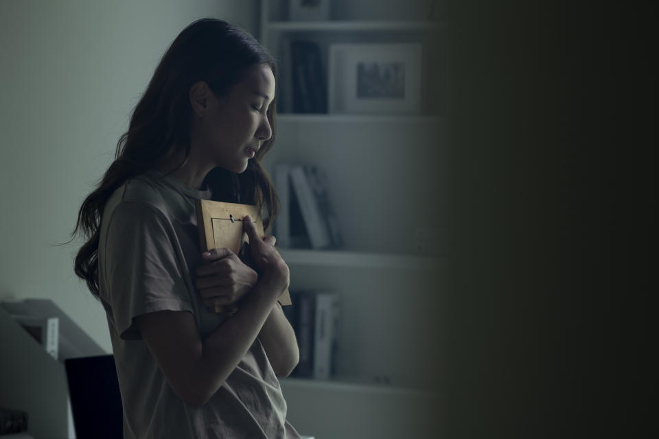 Woman feeling sad when looking at picture of lost loved one in the frame