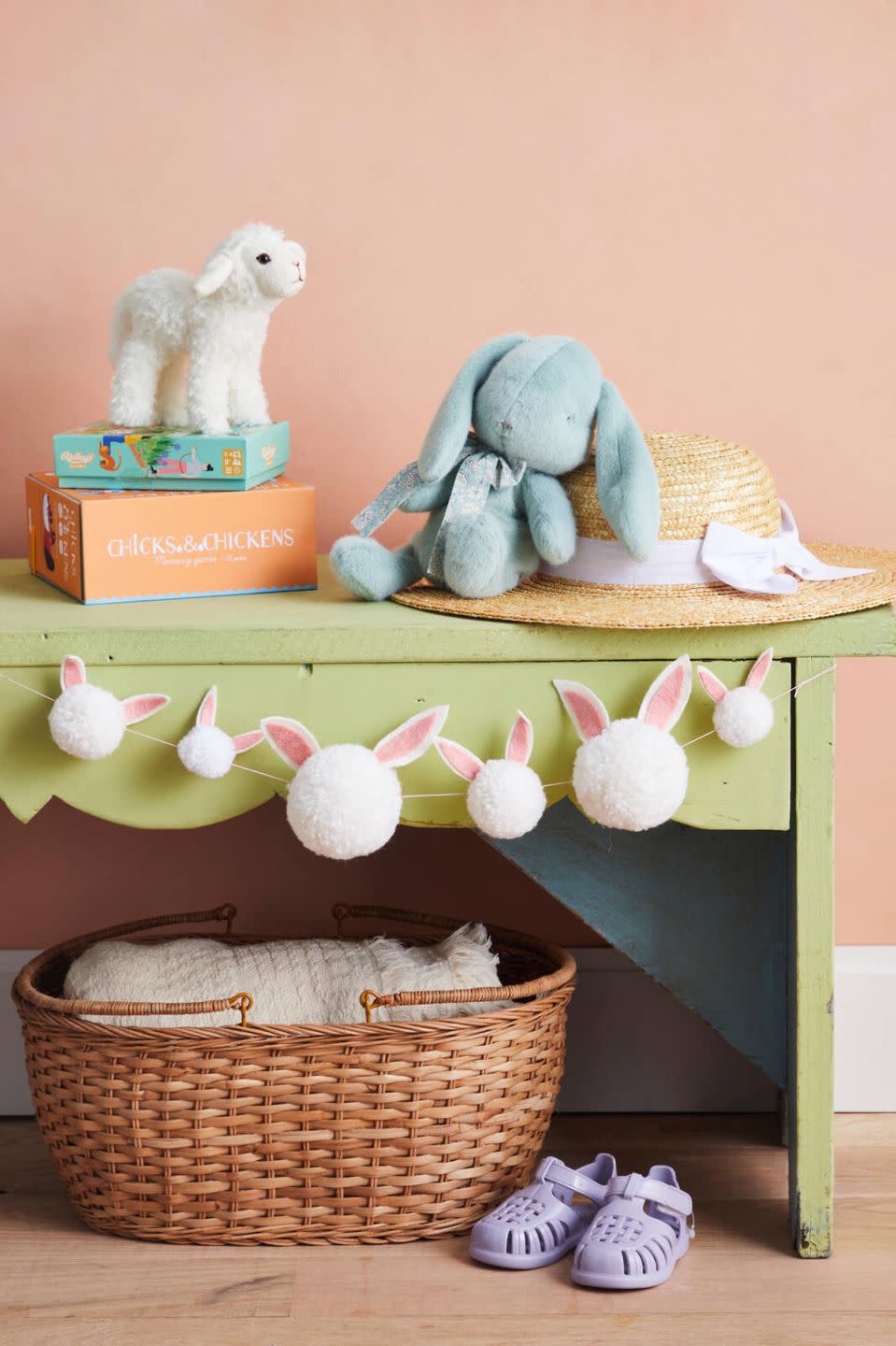 pom pom garland with bunny ears hung on a bench with easter decorations scattered around