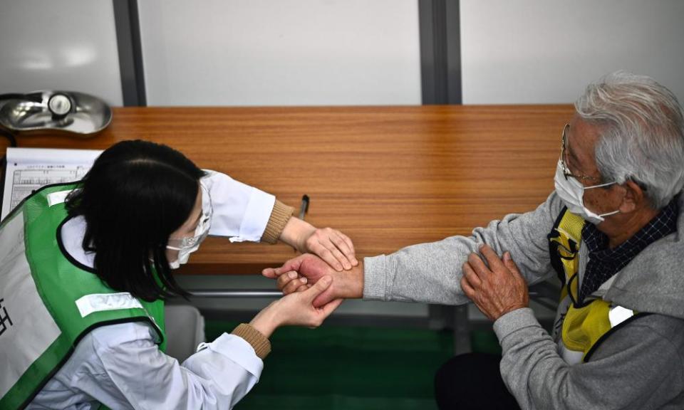 A doctor inspects a man participating in a Covid vaccination drill at the Kawasaki City College of Nursing