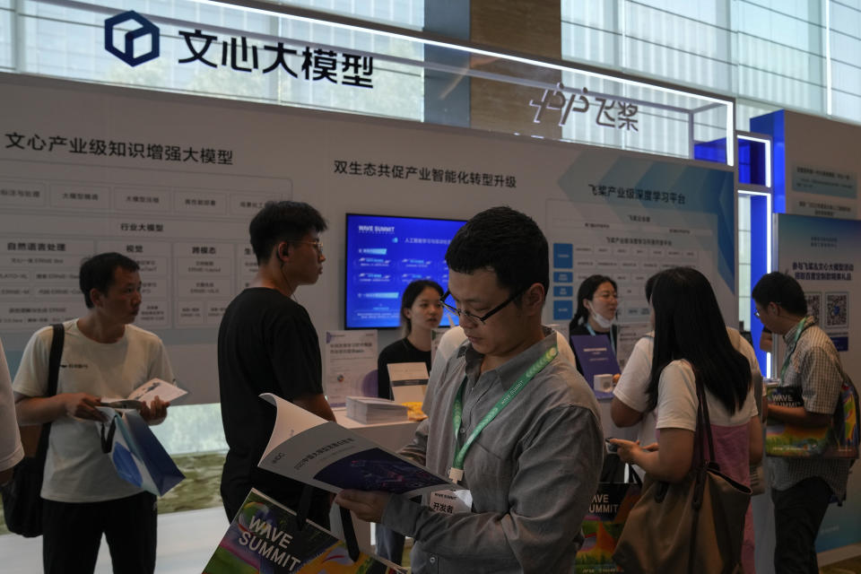 Visitors check out the AI chatbot Ernie Bot at a booth promoting the AI chatbot during the Wave Summit in Beijing on Aug. 16, 2023. Chinese search engine and artificial intelligence firm Baidu made its ChatGPT-equivalent language model fully available to the public Thursday, Aug. 31, raising the company’s stock price by over 3% following the announcement. (AP Photo/Andy Wong)
