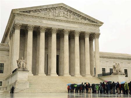 People line up in the rain outside of the U.S. Supreme Court in Washington in this April 29, 2014 file photo. REUTERS/Gary Cameron/Files