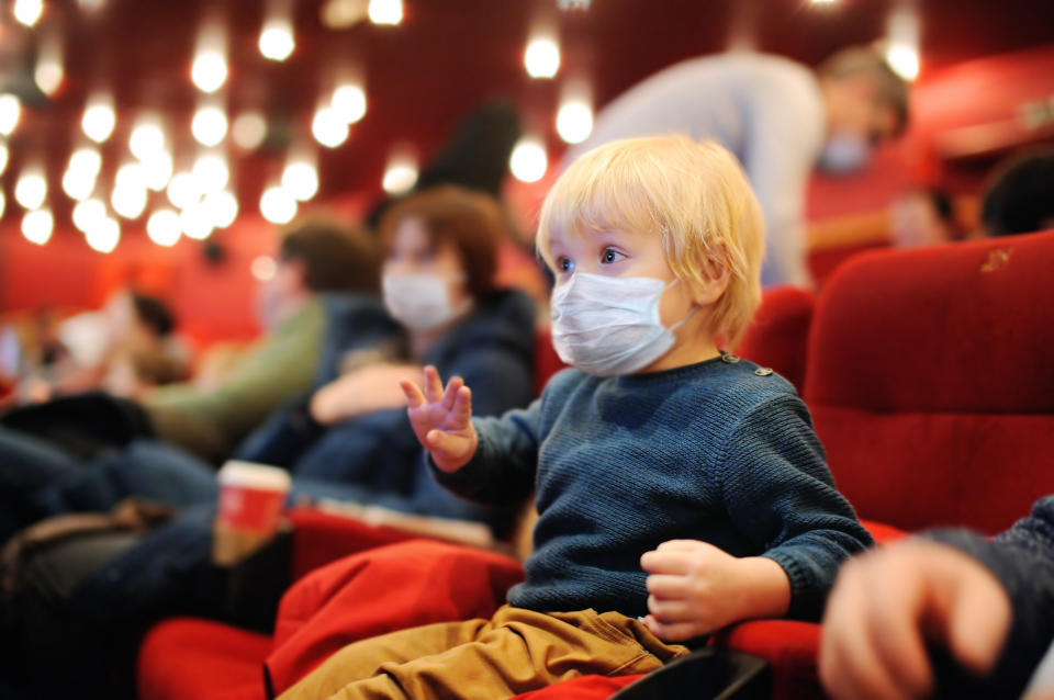 A young child in a movie theater wearing a mask