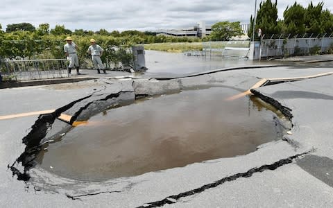 Water fills a crack on a road that opened up after the tremor - Credit: KYODO/ REUTERS