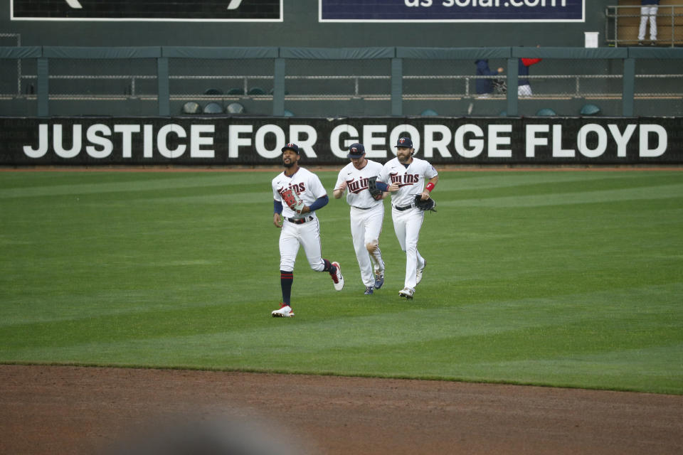 Minnesota Twins' Byron Buxton, Kyle Garlick, and Jake Cave, left to right, celebrate the 10-2 win over Seattle Mariners in front of a Target Field sign that reads "Justice for George Floyd" at a baseball game Thursday, April 8, 2021, in Minneapolis. (AP Photo/Bruce Kluckhohn)