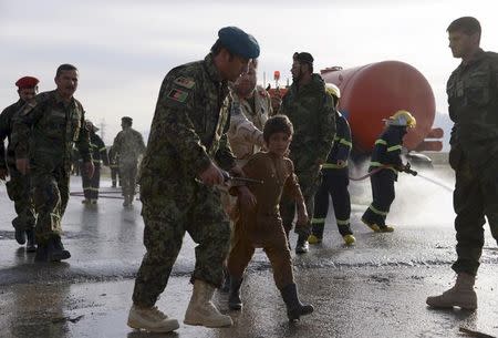 An Afghan National Army officer escorts a slightly injured boy from the site of a suicide attack on the outskirts of Mazar-i-Sharif, Afghanistan February 8, 2016. REUTERS/Anil Usyan