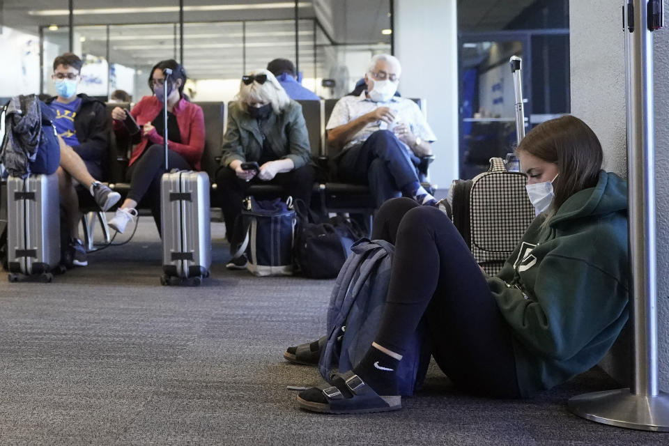 Passenger Cari Driggs, right, from Provo, Utah, waits to board a United Airlines flight to Hawaii for vacation at San Francisco International Airport in San Francisco, Thursday, Oct. 15, 2020. Coronavirus weary residents and struggling business owners in Hawaii will be watching closely as tourists begin to return to the islands on Thursday without having to self-quarantine upon arrival. (AP Photo/Jeff Chiu)