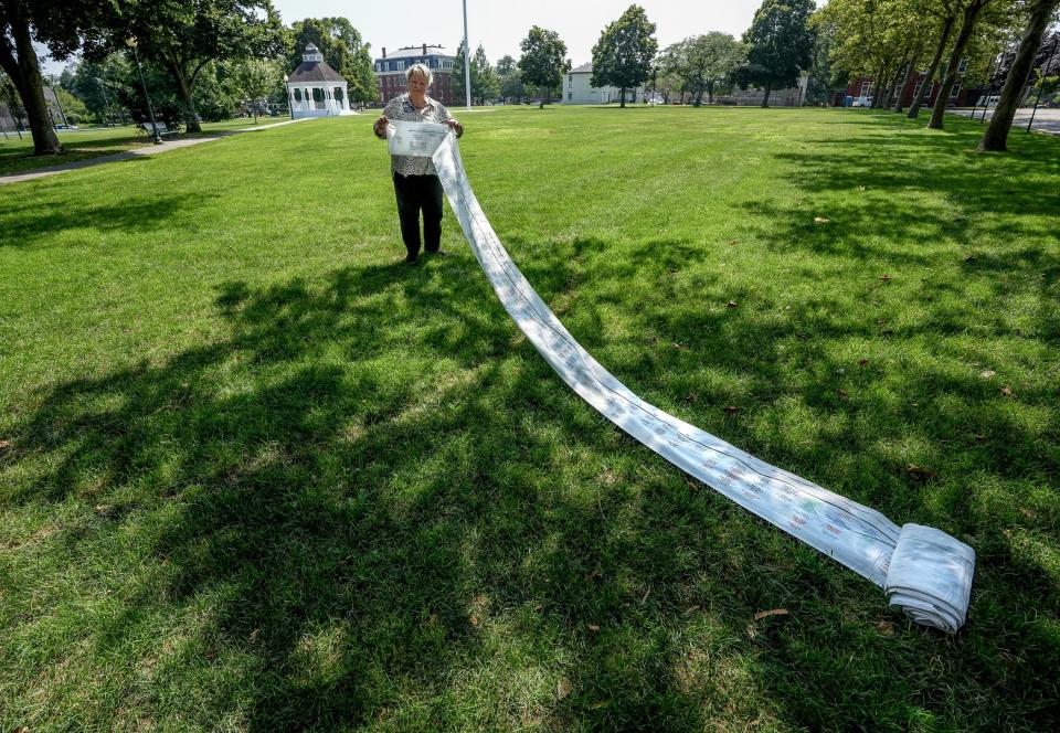 Lynn Smith, who serves on the board of Linden Place, unfurls a "timeline of enslavement," a 52-foot banner bearing the names of people who were enslaved in Bristol between 1680 and 1808. Smith will soon lead a walking tour featuring the New Goree neighborhood of Bristol, a settlement of free Blacks who began settling in the town in the early 1800s.