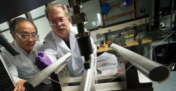 Two Corning scientists to bend a sheet of glass for testing in the laboratory.