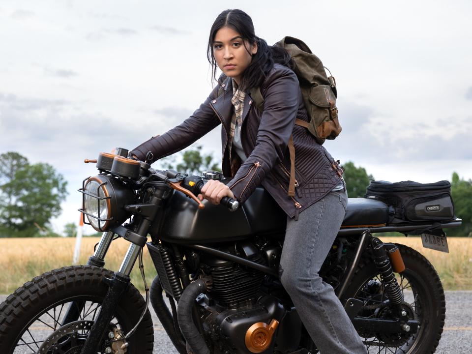 a woman on a motorcycle wearing a backpack, looking intently