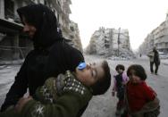 A Syrian woman and her children walk past the ruins of buildings in Aleppo on January 21, 2017