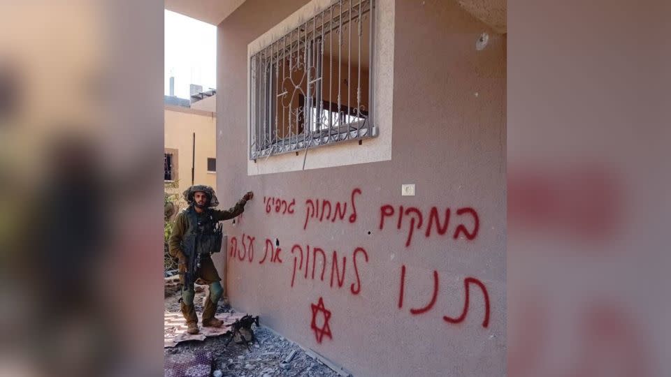 An image shared online shows an Israeli soldier next to a sign that says "Instead of erasing graffiti, let us erase Gaza." - Obtained by CNN