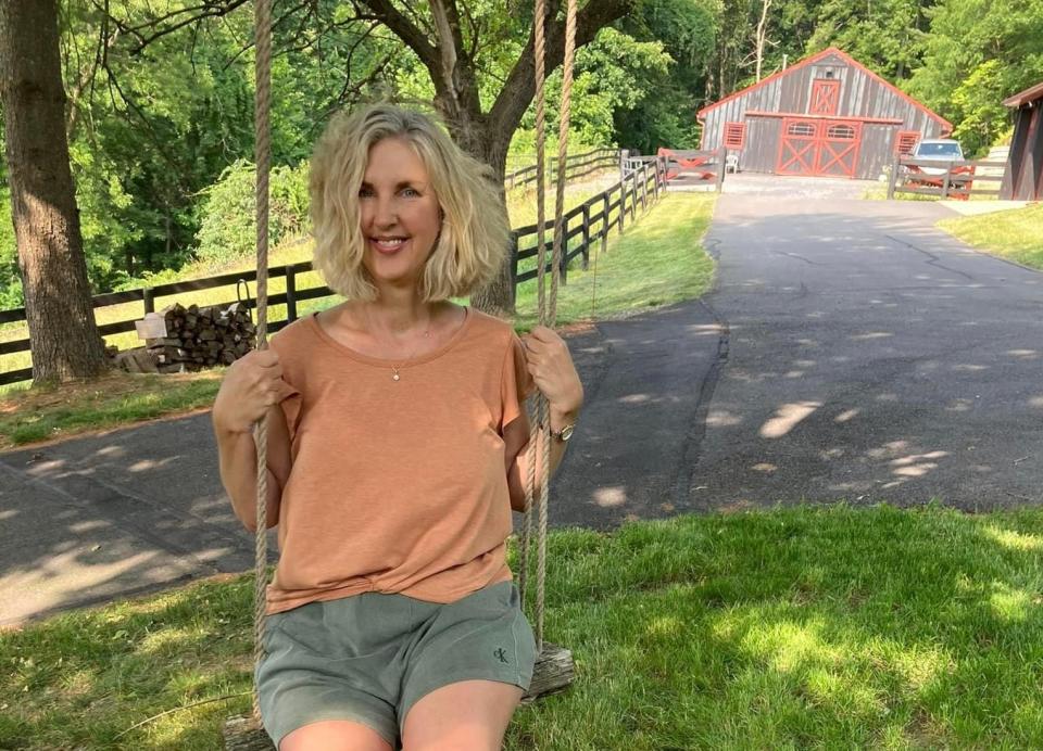 Author Courtenay Rudzinski on a swing in front of green grass