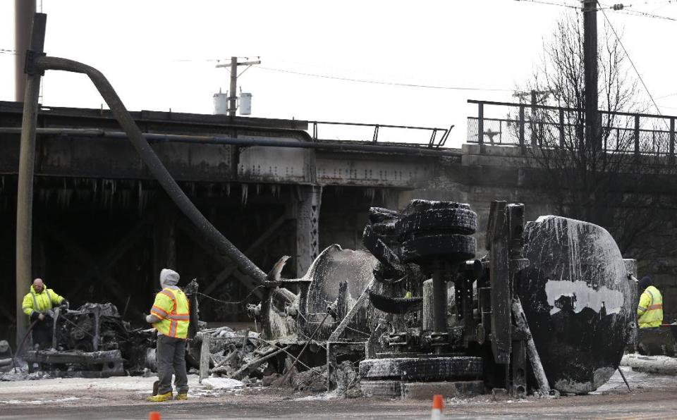 Crews clean up the site where a tanker overturned and burst into flames early in the morning near train tracks on Route 21 in Newark, N.J., Thursday, March 13, 2014. The tanker burst into flames after colliding with a car on McCarter Highway adjacent to Amtrak's Northeast Corridor rail line in Newark at about 1:45 a.m. Thursday. That caused problems for Amtrak's signals and overhead wires. Amtrak service is running with minor delays. (AP Photo/Julio Cortez)