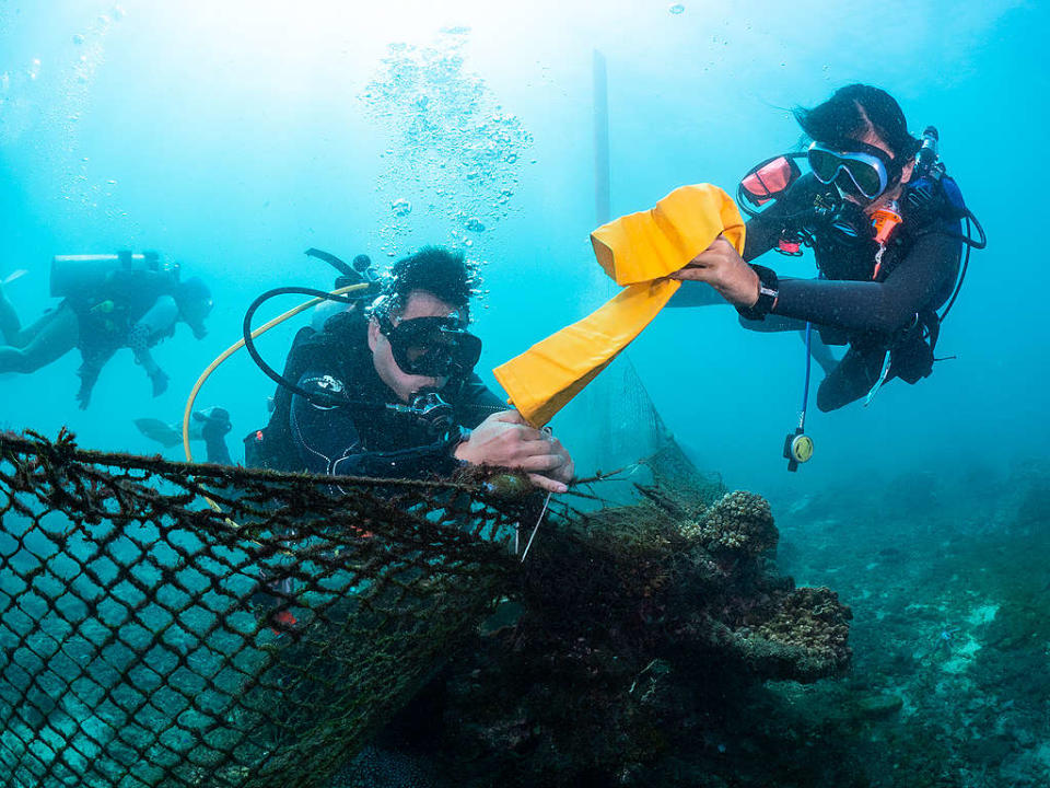 潛水志工正進行水下廢棄漁網清除作業，並使用浮力裝置讓大型廢棄物浮至水面
