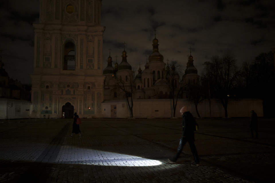 A woman walks with a flashlight during a power outage in Kyiv, Ukraine, Wednesday, Dec. 14, 2022. (AP Photo/Felipe Dana)