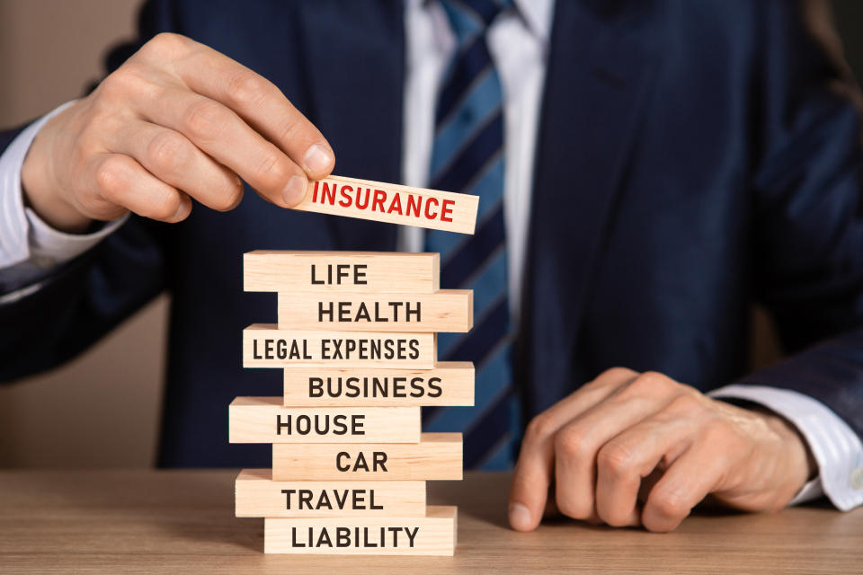 A stack of wooden blocks with words: life, health, legal expenses, business, house, car, travel, liability. Source: Getty Images