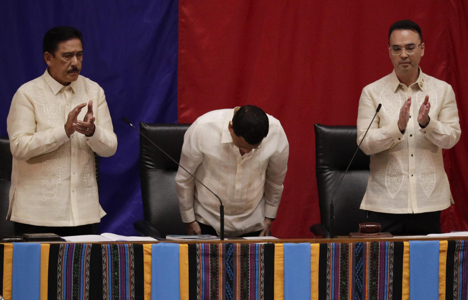 Philippine President Rodrigo Duterte, center, bows before he delivers his 4th State of the Nation Address as Senate President Vicente Sotto III, left, and House Speaker Allan Peter Cayetano applaud at the House of Representatives in Quezon city, metropolitan Manila, Philippines Monday July 22, 2019. (AP Photo/Aaron Favila)