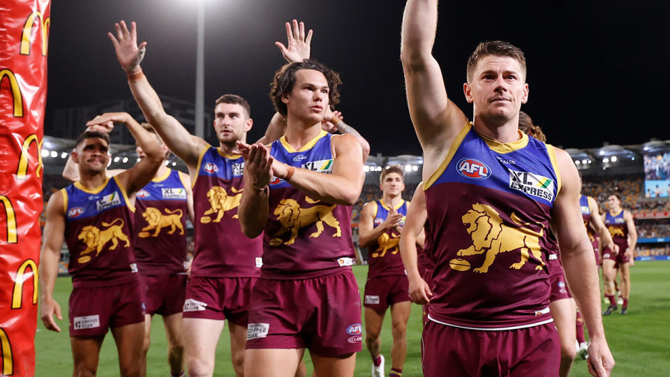 The Brisbane Lions are pictured waving to fans as they leave the field.
