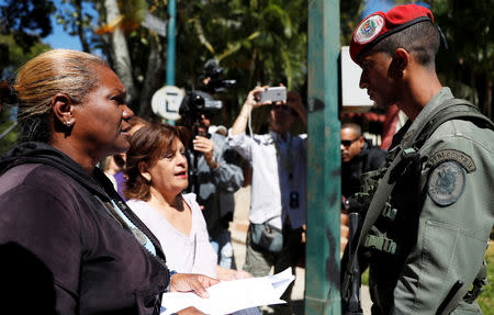 Supporters of Venezuelan opposition leader and self-proclaimed interim president Juan Guaido explain a document regarding a proposed amnesty law for members of the military, police and civilians as they talk to the solider outside the Presidential Residence in Caracas, Venezuela, January 27, 2019. REUTERS/Carlos Garcia Rawlins