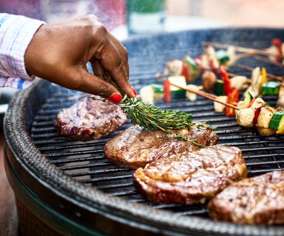 A gas grill with meats and vegetables on it