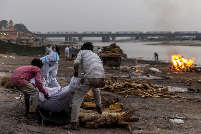 People place the body of a man who died from the coronavirus disease (COVID-19), on a pyre before his cremation on the banks of the river Ganges at Garhmukteshwar