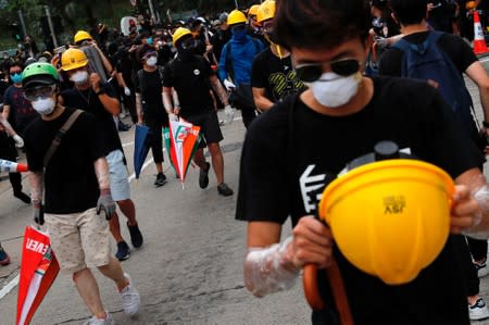 Anti-extradition bill protesters wear helmets to protect themselves from riot police after a march at Sha Tin District of East New Territories, Hong Kong