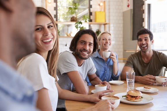 Group of millennial adults, sitting around a table.