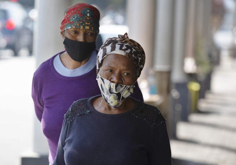 Women wearing face masks walk on a suburban sidewalk in Johannesburg, South Africa on Wednesday, July 22, 2020. Ordinarily, South Africa sees widespread influenza during the winter months, but this year almost none have been found — something unprecedented. School closures, limited public gatherings and calls to wear masks and wash hands have “knocked down the flu,” said Dr. Cheryl Cohen, head of the institute's respiratory program. (AP Photo/Denis Farrell)