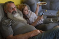 Joe Smith sits on the sofa with his granddaughter Olivia in their home in Columbus, Ohio, Tuesday, Oct. 24, 2023. Smith did not picture raising Olivia, but when his daughter's substance use disorder meant she couldn't care for her child, that's where Smith and his wife found themselves nineteen years ago. (AP Photo/Carolyn Kaster)