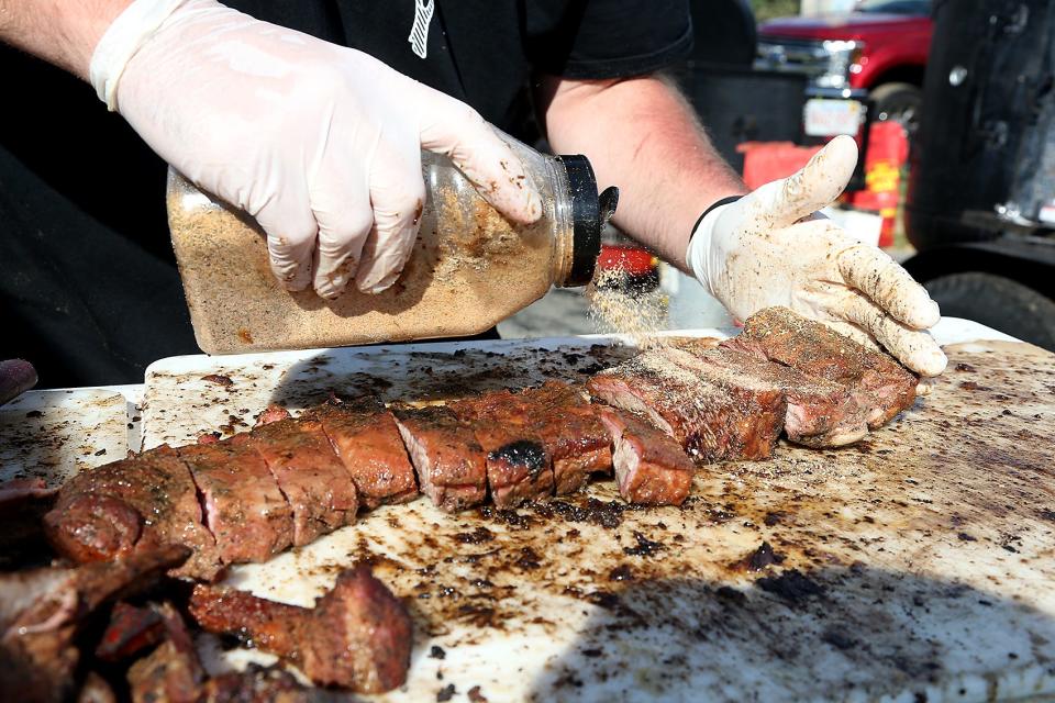 Hunter Daniels, of Mear Bro’s BBQ in Pembroke, adds a garlic and herb rub to the North Carolina mustard-style ribs they were serving at the Marshfield Community Rib Cook-Off at the Marshfield Fairgrounds on Saturday, Sept. 11, 2021.