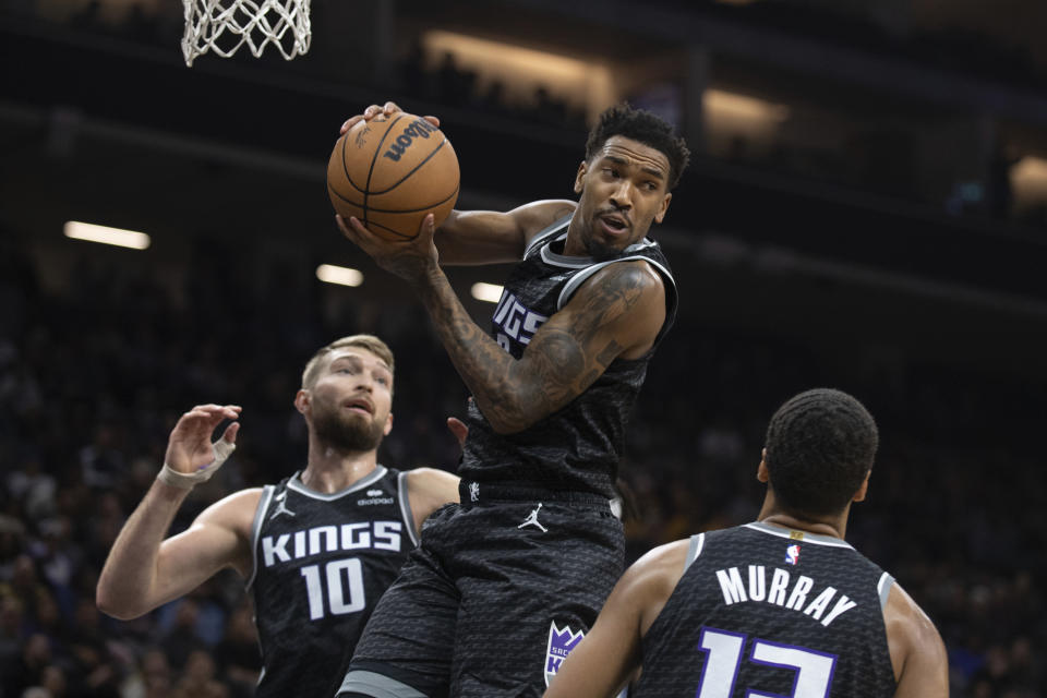 Sacramento Kings guard Malik Monk, top, pulls down a rebound between forward Domantas Sabonis (10) and forward Keegan Murray (13) in the first quarter in an NBA basketball game against the Orlando Magic in Sacramento, Calif., Monday, Jan. 9, 2023. (AP Photo/José Luis Villegas)