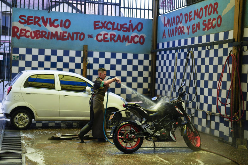 A worker washes a motorcycle at an ecological carwash in Bogota, Colombia, Friday, April 12, 2024. Water rationing in the capital began on Thursday due to the low level of water in reservoirs that give drinking water to the capital, a consequence of the El Niño weather phenomenon. (AP Photo/Fernando Vergara)