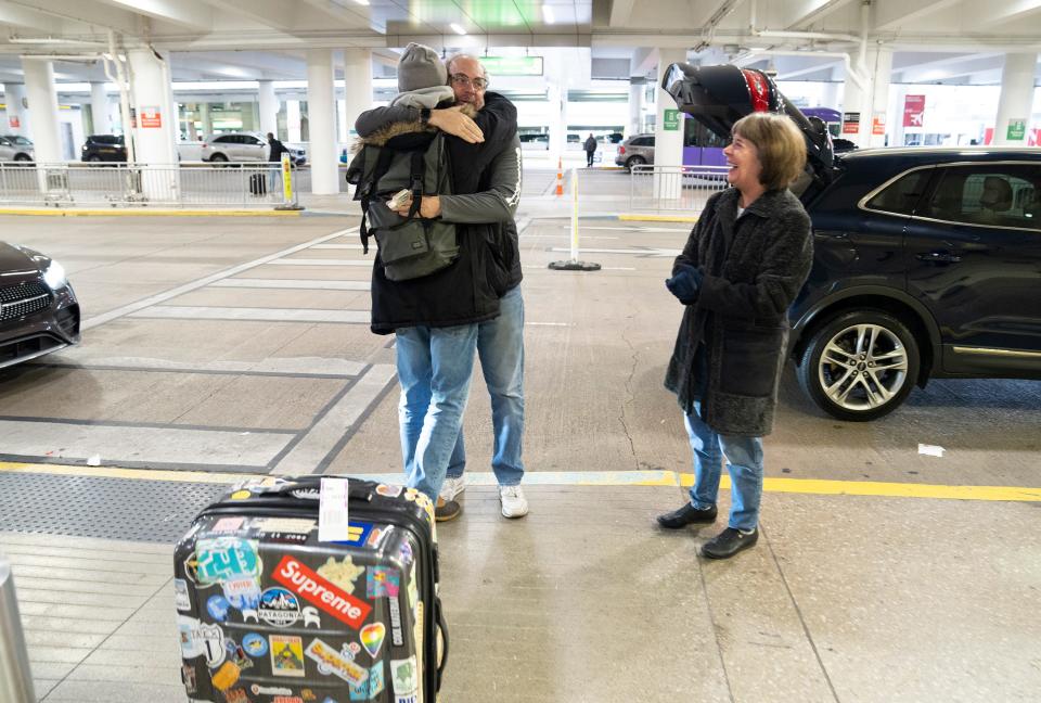 Nick Levitt, center, greets his father, Mitch Levitt, while his mother, Patty Levitt, smiles at John Glenn Columbus International Airport. Nick was able to fly into Columbus from Chicago, but he and his family are worried that his brother and his wife may face weather problems on their planned flight from Baltimore on Friday.