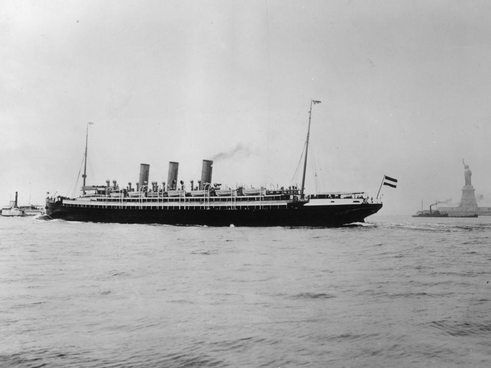 A 19th century ocean liner in the water of New York Harbor near the Statue of Liberty