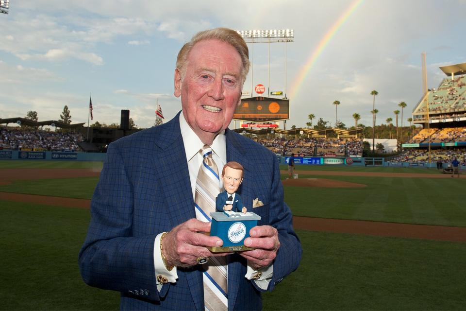 At Dodger Stadium with a rainbow over his shoulder Sportscaster Vin Scully poses for a portrait with a bobblehead of himself on August 30, 2012 in Los Angeles, California.