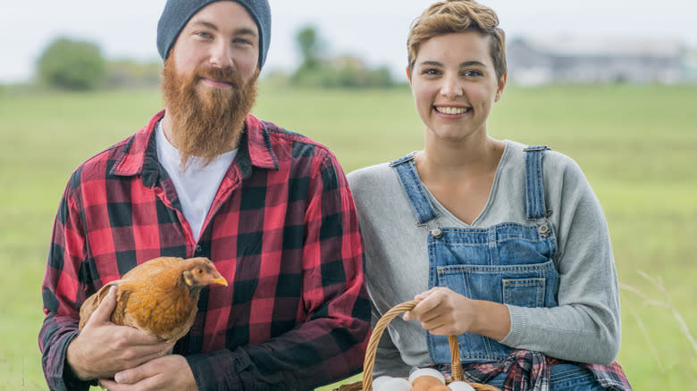 Farmers holding a chicken and eggs