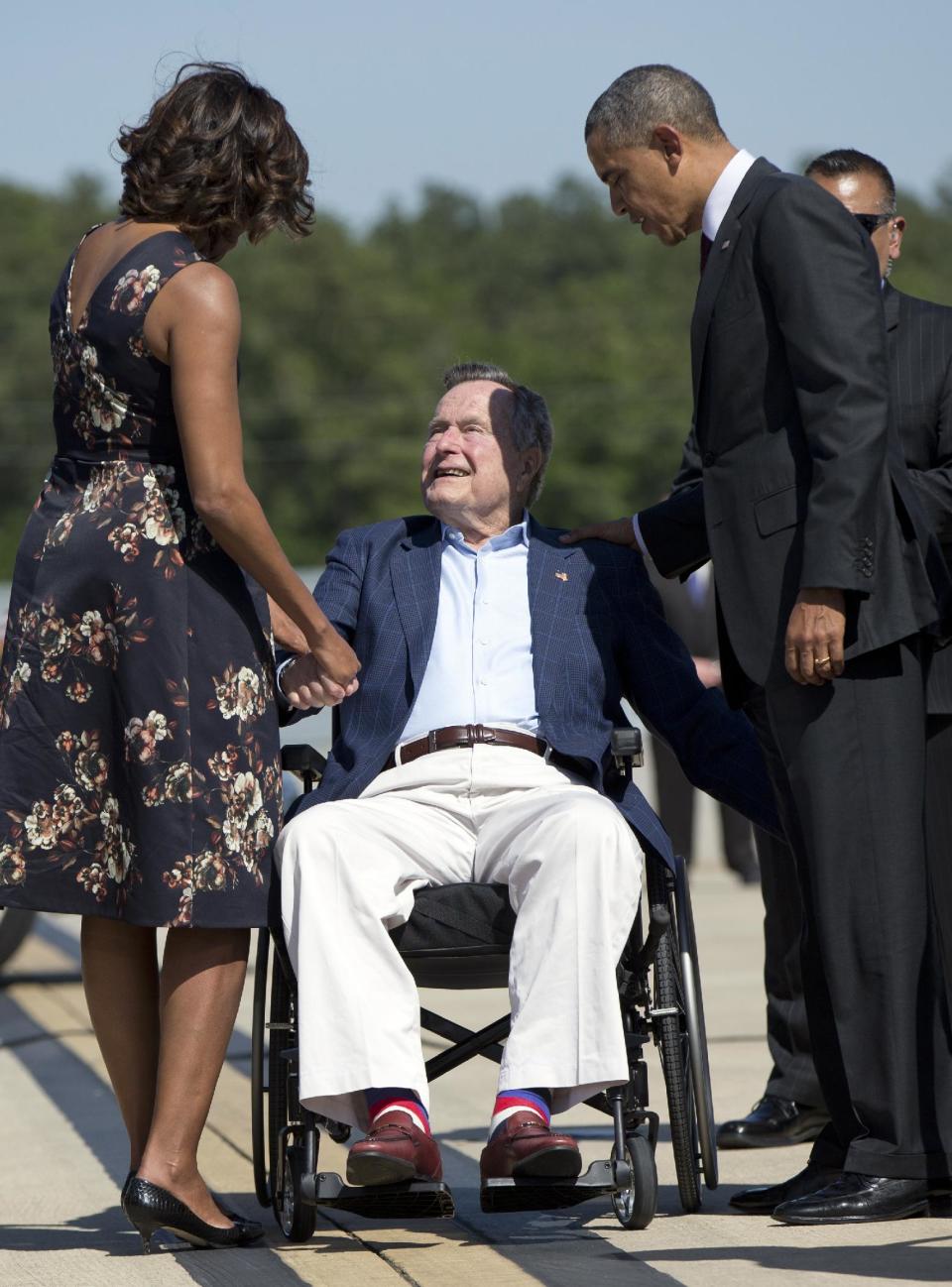 President Barack Obama and first lady Michelle Obama are greeted by former President George H.W. Bush as they arrive on Air Force One at George Bush Intercontinental Airport, Wednesday, April 9, 2014, in Houston. (AP Photo/Carolyn Kaster)