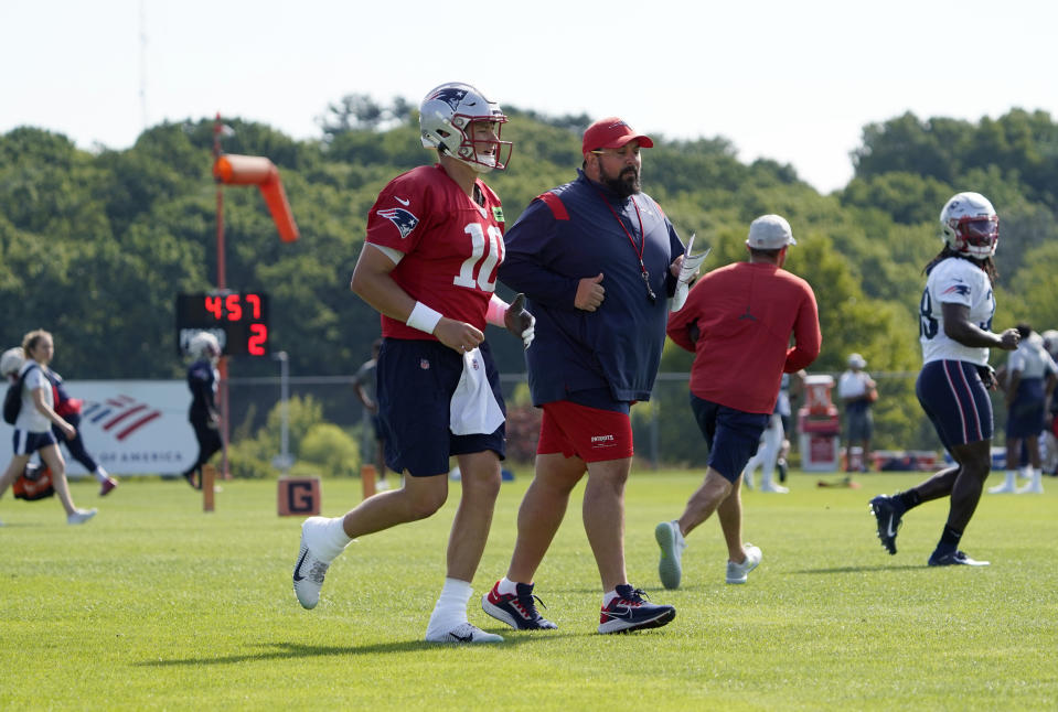 New England Patriots quarterback Mac Jones runs with Senior Football advisor Matt Patricia as Jones takes part in drills at the NFL football team's practice facility in Foxborough, Mass., Saturday, July 30, 2022. (AP Photo/Mary Schwalm)