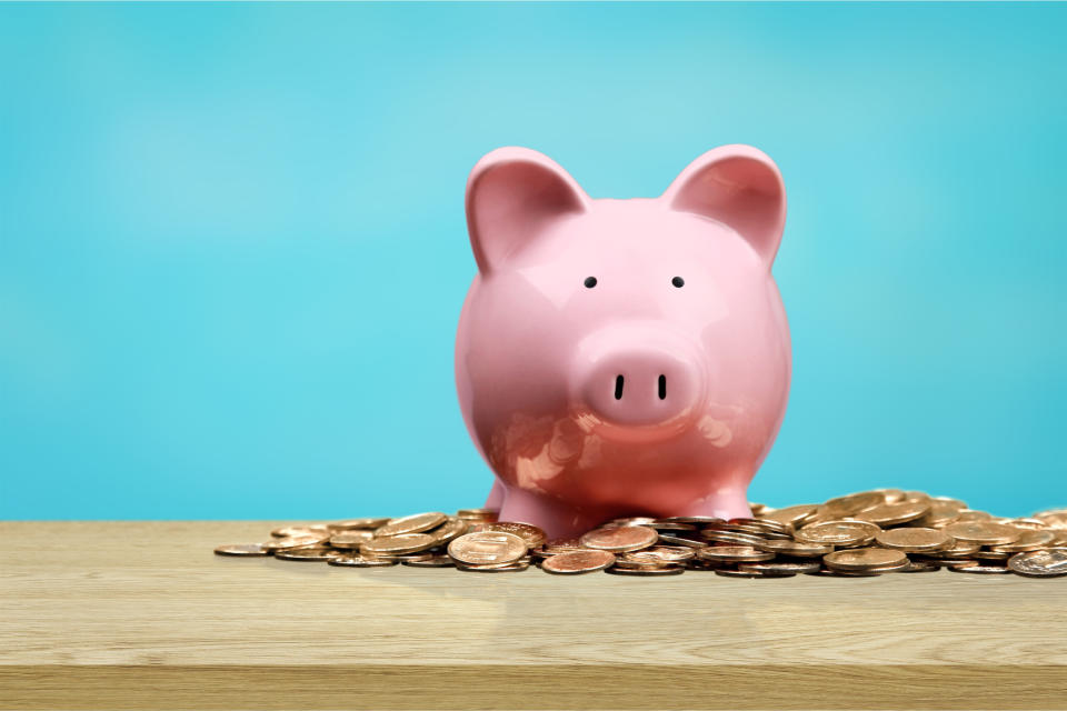 A pink piggy bank on top of a pile of coins.