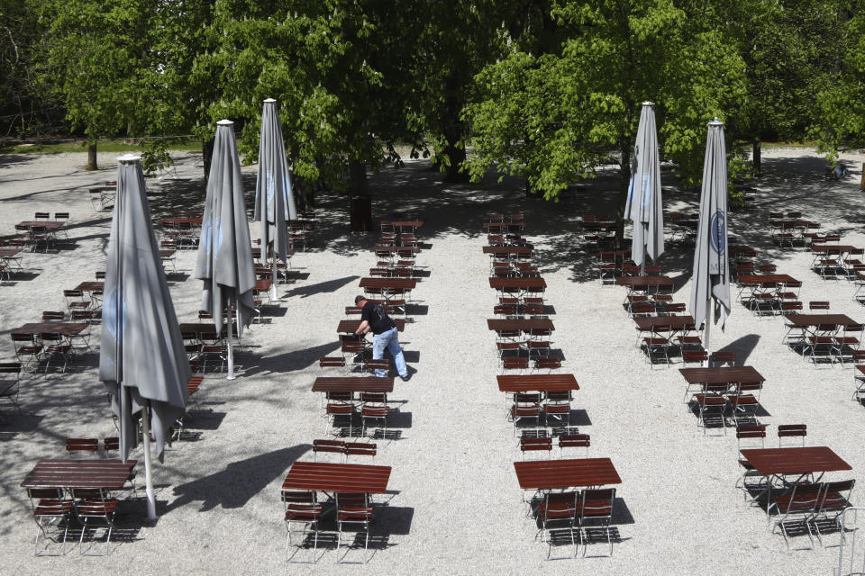 An employee of the 'Taxisgarten' beer garden prepares benches and tables for the re-opening in Munich, Germany, Monday, May 10, 2021. (AP Photo/Matthias Schrader)