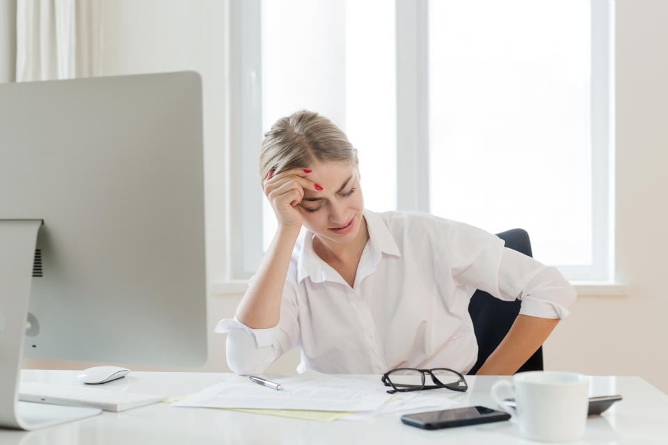 Woman at desk with digestion issues. (Getty Images)