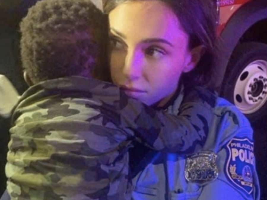 A Philadelphia police officer holding the son of a mother, Rickia Young, who was allegedly beaten during anti-racism demonstrations in Philadelphia last year  (Cafemom/Philadelphia city police)