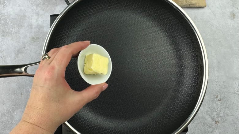 hand putting butter in pan