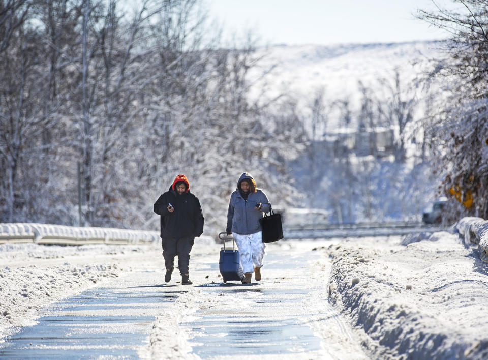 Kiara Davis and Aja Brown walk up the I-95 on-ramp with a cooler with beverages and snacks for stranded drivers.