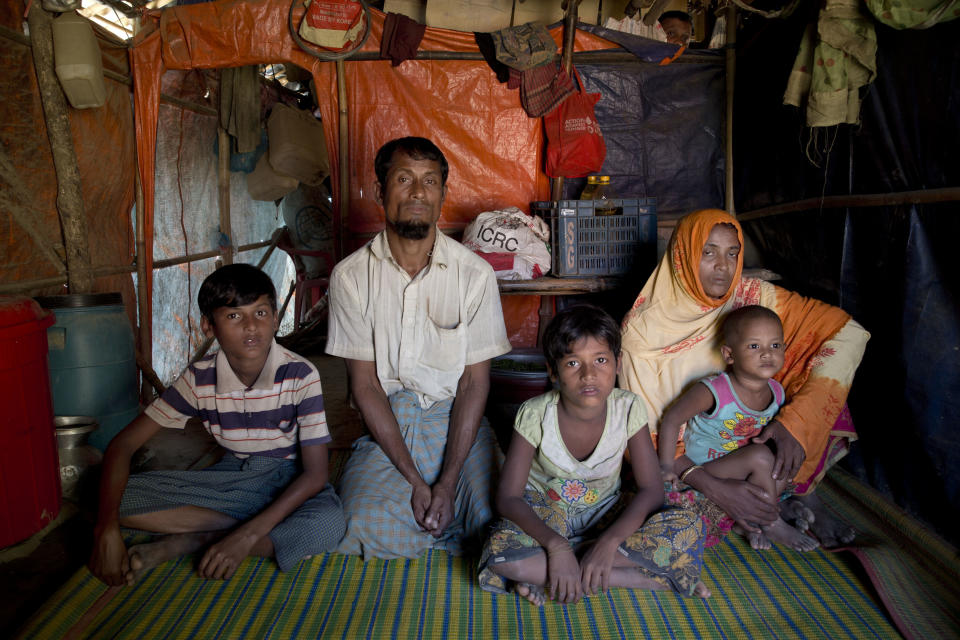 A Rohingya Muslim man Nabi Hossain sits for a photograph along with his family inside Unchiprang refugee camp near Cox's Bazar, in Bangladesh, Friday, Nov. 16, 2018. Normal life returned to a Rohingya Muslim refugee camp in Bangladesh on Friday a day after government officials postponed plans to begin repatriating residents to Myanmar when no one volunteered to go. Hossain fled his shanty at the camp on Wednesday with his family fearing they would be repatriated back to Myanmar but returned upon hearing news of protests against the process. (AP Photo/Dar Yasin)